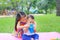 Adorable Asian sister sitting on pink mattress mat take care her little brother to drinking water from Baby sippy cup with straw i