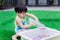 Adorable Asian toddler boy playing with sensory water bead. Cute child pours a plastic bottle  pouring orbiting into a white basin