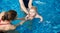 Adorable baby boy enjoying swimming in paddling pool with his mother and instructor. Child swimming trainer in action