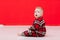 adorable baby boy in red checked pyjamas sitting and playing with Christmas toy in hand. Little child is having fun on