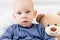 Adorable baby boy sitting on a bed, playing with toy bears on a bed. Newborn child portrait.