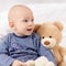 Adorable baby boy sitting on a bed, playing with toy bears on a bed. Newborn child relaxing on a bed.
