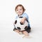 Adorable baby boy sitting with soccer ball