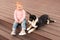 Adorable baby and furry little dog on wooden porch
