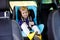 Adorable baby girl with blue eyes sitting in car safety seat. Toddler child going on family vacations and jorney. Happy