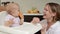 Adorable baby girl eating orange. Little daughter sitting in feeding chair and eating slice of orange at kitchen and