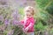 Adorable baby girl with purple flowers in heather land