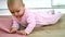 Adorable baby lying on the wooden floor and biting a pink mat