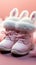 Adorable baby pink booties for tiny feet, resting on a hares cap