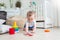 Adorable baby playing on floor with colorful rings from toy pyramid tower