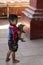 Adorable barefoot small Burmese boy seen in profile in temple holding a tiny puppy