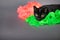 Adorable black house cat laying head down on neon green and pink ruffly fabric