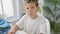 Adorable blond boy student concentrating and taking notes at his desk in classroom setting