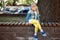 Adorable blond caucasian preschooler fashionista girl wearing jeans and bright yellow leggins sitting over wooden bench and