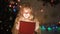 Adorable blond girl opening gift box, magic Christmas atmosphere, glowing effect