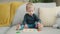 Adorable blond toddler playing with maths game sitting on sofa at home
