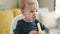 Adorable blond toddler sitting on highchair eating snack at home