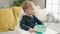 Adorable blond toddler sitting on highchair waiting to eat at home