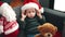 Adorable blond toddler sitting on sofa wearing christmas hat at home