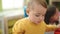 Adorable blond toddler standing with relaxed expression at kindergarten