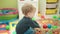 Adorable blond toddler throwing balls standing at kindergarten
