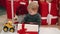 Adorable blond toddler unpacking christmas gift sitting on floor at home