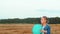 Adorable blonde girl playing with blue ball in wheat field