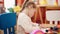 Adorable blonde girl preschool student sitting on table drawing on paper at kindergarten