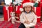 Adorable blonde toddler writing santa claus letter sitting on floor by christmas gifts at home