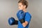 Adorable boy in boxing gloves standing against gray background