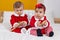 Adorable boy and girl wearing christmas clothes holding rattle at bedroom