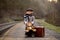 Adorable boy on a railway station, waiting for the train with suitcase and sweet teddy bear