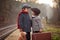 Adorable boy on a railway station, waiting for the train with suitcase and teddy bear