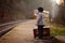 Adorable boy on a railway station, waiting for the train with suitcase and teddy bear