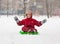 Adorable boy sitting at slide on snowy landscape