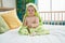 Adorable caucasian baby wearing funny towel sitting on bed at bedroom
