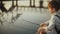 Adorable Caucasian boy plays with stick near lake. Little cute child with backpack on a pier. Happy childhood. 4K.