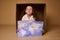 Adorable Caucasian child 4 years old girl sitting inside a cardboard box with a poster- painted image with World map, 