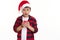 Adorable Caucasian child boy wearing santa hat, making a cherished wish for Christmas and blowing out a red candle