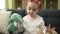 Adorable caucasian girl playing with dolls sitting on sofa at home