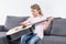 Adorable caucasian girl playing on guitar while sitting on sofa