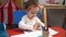 Adorable caucasian girl preschool student sitting on table drawing on paper at kindergarten