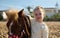 Adorable Caucasian kid girl hugging a little pony, smiling looking at camera, enjoying a happy family weekend outdoor.