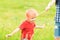 Adorable Caucasian kid playing with scoop-net on the meadow on warm and sunny summer or spring day.