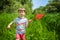 Adorable Caucasian kid playing with scoop-net on the meadow on warm and sunny summer or spring day.