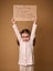 Adorable Caucasian preschool girl holding cardboard poster promoting children`s rights to an adequate standard of living, social
