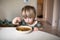 Adorable caucasian toddler boy eating healthy soup in the kitch