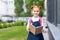 adorable cheerful redhead schoolgirl holding book and smiling