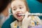Adorable child calmly goes through procedure of teeth polishing