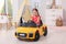 Adorable child driving toy car in room at home